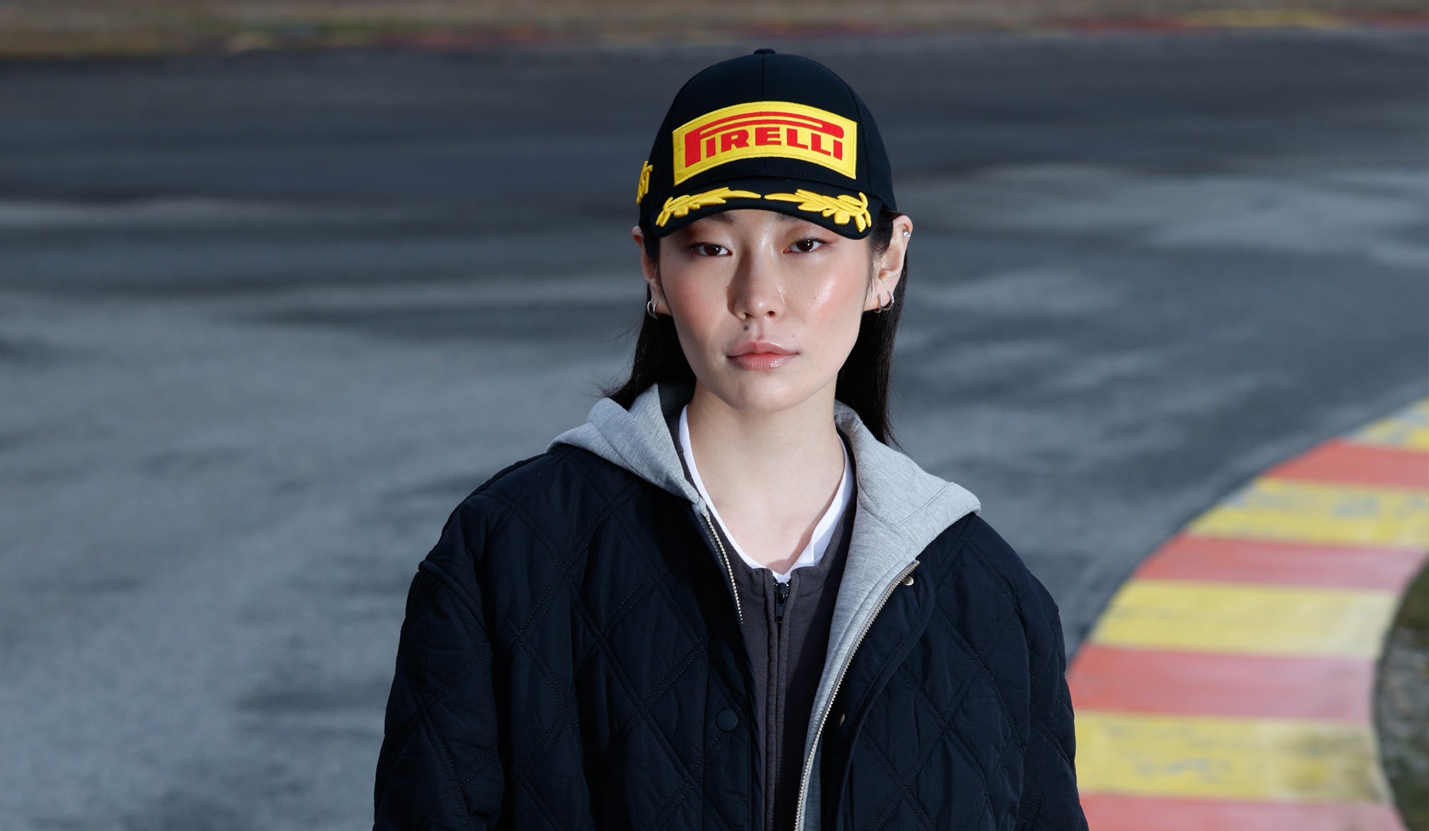 Woman at racetrack in black Pirelli Podium Cap